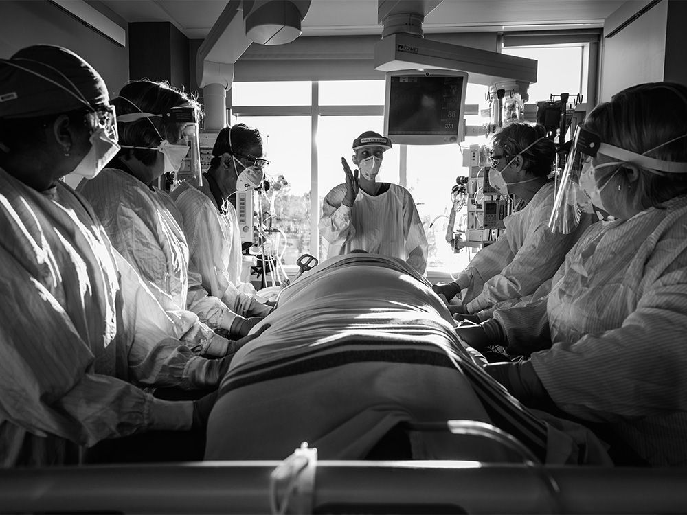 officials prepare for the proning of a covid-19 patient. excerpts were originally published in shadows and light: a physician’s lens on covid copyright © 2022 by heather patterson. reprinted by permission of goose lane editions.