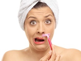 Shocked woman shaving lip with hair wrapped in a white towel