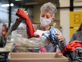 Volunteers working with food and clothes in community charity donations center
