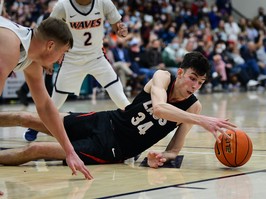 Chet Holmgren, wearing a jeasr with the number 34, lies on the basketball court as he reaches for the ball. Holmgren is currently out for a Lisfranc injury.