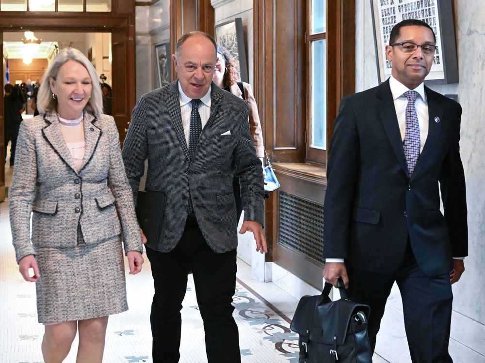 quebec health minister christian dubé, flanked by quebec social services minister lionel carmant, right, and junior health and seniors minister sonia bélanger, walks to a news conference, wednesday, oct. 26, 2022 at the legislature in quebec city.