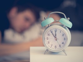 alarm clock with a man sleeping in the background