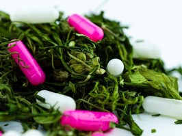 Macro photo of a large pile of buds and marijuana leaves with multi-colored pills in bulk. The concept of replacing opioids with cannabis