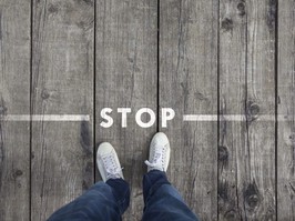 Man standing on the wooden boards with stop message on the floor, point of view perspective used.