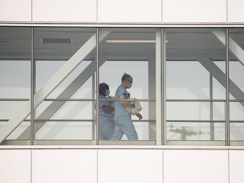 health-care workers walk across a sky bridge at a hospital in montreal.