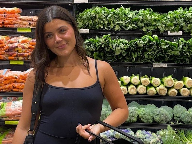 gut expert olivia hedlund at grocery store with produce behind her.