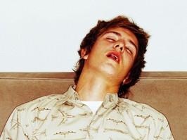 portrait of a young man asleep on the couch after drinking too much beer