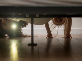 Mother and daughter shine a flashlight looking under the bed