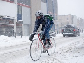 person on a bicycle rides through a winter storm
