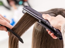 stylist using flat iron on hair