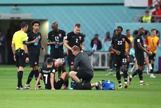 Stephen Eustaquio of Canada sits on the WOrld Cup pitch during a game against Croatia; he is tended to by a medical professional