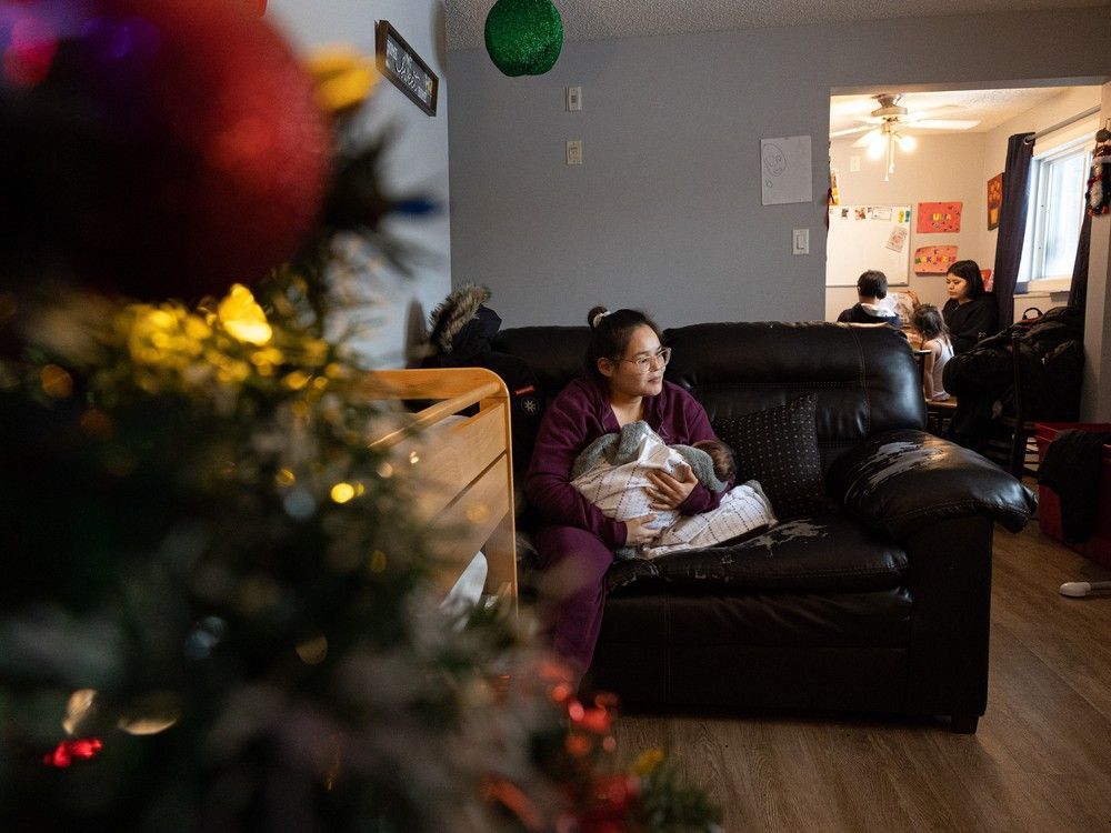 deprise houle holds her two-month-old baby george in her family's new home, which is decorated for christmas.