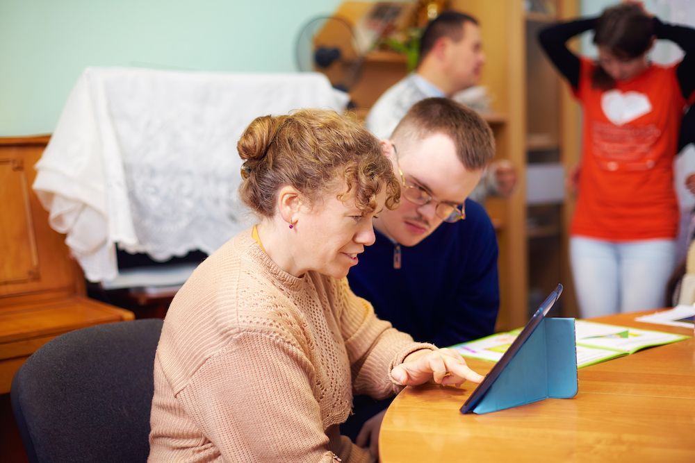 Two friends with disability in rehabilitation centre watching digital tablet.