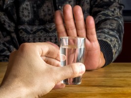 Man's hand rejecting a glass of alcoholic beverage. Concept