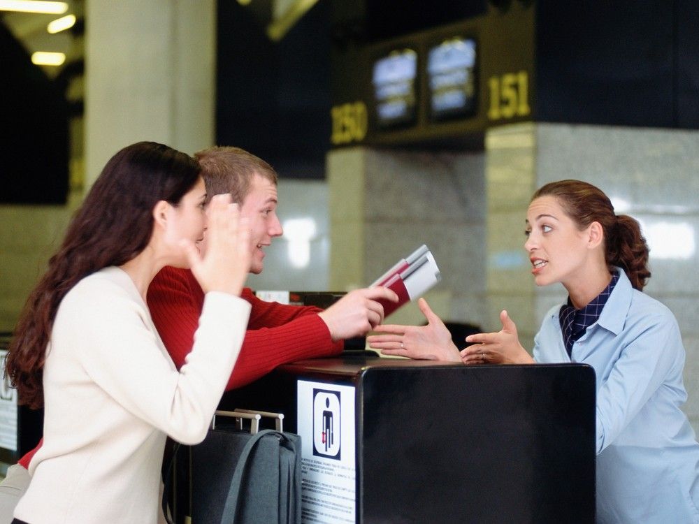 trouble at the check-in desk as travellers complain to airline customer service agent.