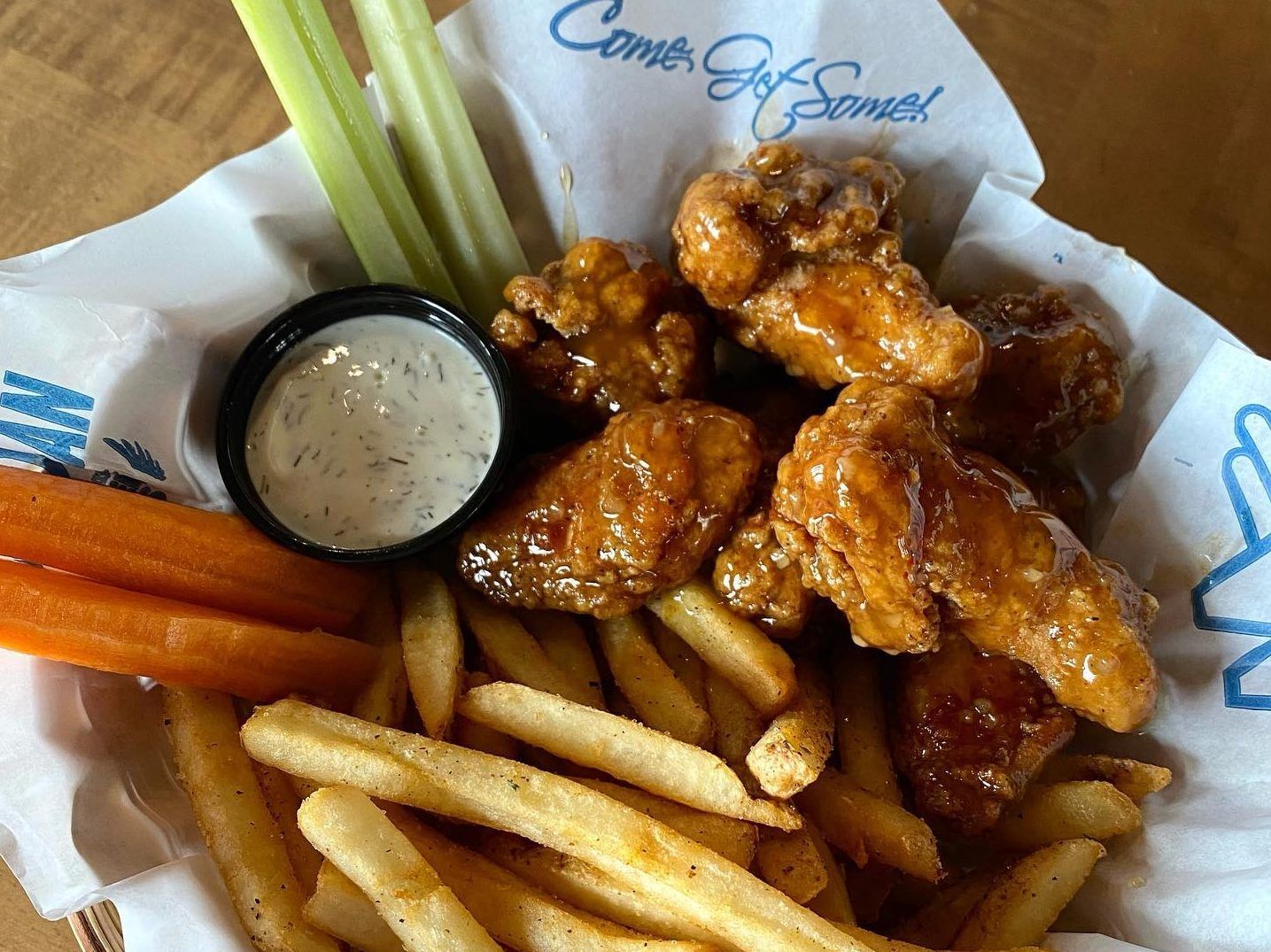 basket of chicken wings, fries, carrot and celery sticks and dip from wild wing.