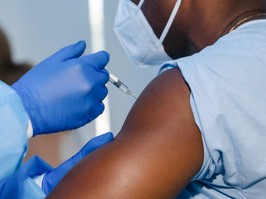 hand of medical staff in blue glove injecting coronavirus covid-19 vaccine in vaccine syringe to arm muscle of african american man for coronavirus covid-19 immunization