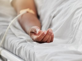 Closeup shot of the hand of an african american woman lying in a hospital bed inside of a ward.