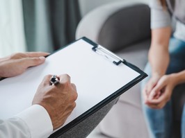 Professional psychologist doctor holding clipboard and filling medical patient information consulting his depressed patient