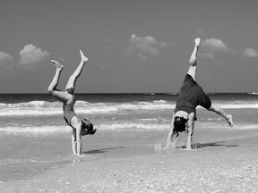 two people doing cartwheels on the beach