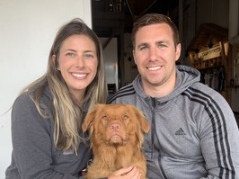 Catherine Perka, who was diagnosed with stage three colorectal cancer, and her husband Dan sit at a table holding their dog.