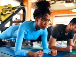 Women and man in sportswear doing plank exercise on rubber mat in fitness club. Should gym memberships receive a tax credit?