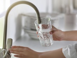 person filling a glass with water