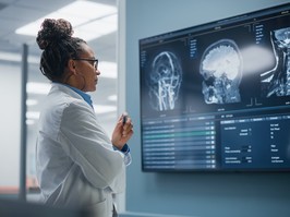 A Neurosurgeon looks at TV Screen with MRI Scan with Brain Images, using AI to help sift through the troves of patient data available