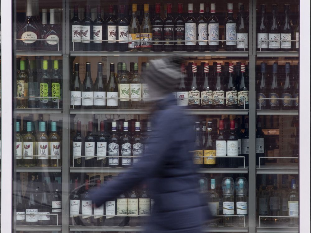 a person walks past shelves of bottles of alcohol on display at an lcbo in ottawa.