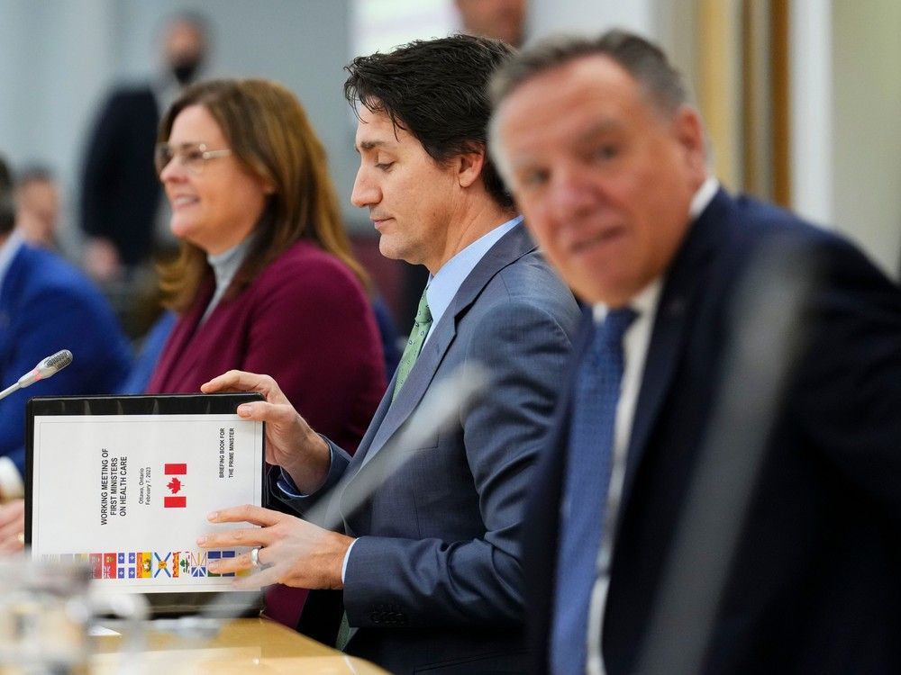 prime minister justin trudeau flips open a briefing book titled 'working meeting of first ministers on health care' as he meets with canada's premiers in ottawa on tuesday, feb. 7, 2023 in ottawa. manitoba premier heather stefanson sits to his right and quebec premier francois legault to his left.