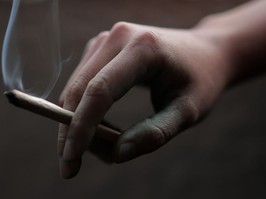 Hand holding a light cannabis joint.