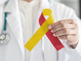 Red and yellow ribbon in medical doctor hand symbolic bow color to support patient with illness and hepatic disease
