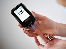 Person using a glucometer to measure blood sure levels.