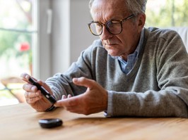 Man checks his blood sugar levels by pricking his finger to draw blood for a glucometer.