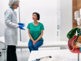 Gastroenterology consultation. Anatomical model of pancreas on doctor table over background gastroenterologist consulting woman patient with gastrointestinal disorders