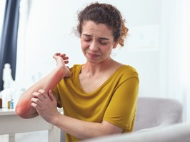 Young girl feeling helpless to resist the itchiness caused by the rash on her elbow and wrist.