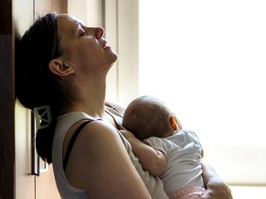 Tired concerned mother rocking sleeping baby.