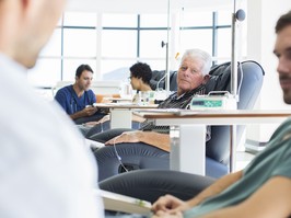 Doctors talking to patients receiving medical treatment in hospital ward