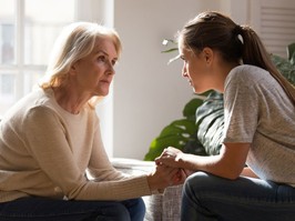 Grown up daughter holding hands of middle aged mother relatives female sitting look at each other having heart-to-heart talk, understanding support care and love of diverse generations women concept