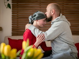 Supportive husband kissing his wife, cancer patient, after treatment in hospital. Cancer and family support concept.