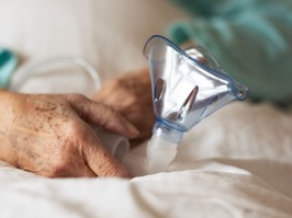 Close-up of oxygen mask holding by eldery patient in hospital. Home oxygen therapy.