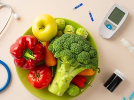 Diabetes Supportive Equipment: Top view photo showcasing a blue ribbon, glucometer, lancet pen, needles, strips, stethoscope, and a plate of broccoli, pepper