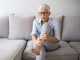 Middle-aged woman suffering from pain in leg at home