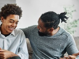 Portrait of a happy teenage boy son talking to his father at home. Sharing secrets and having fun, support and parenthood concept