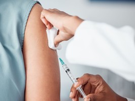 Closeup of a nurse doing a vaccination injection with a needle syringe in a medicare hospital.