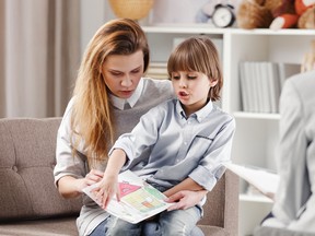 Mother with autistic child holding a drawing during consultation with psychotherapist