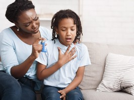 Black mother holding asthma inhaler for daughter