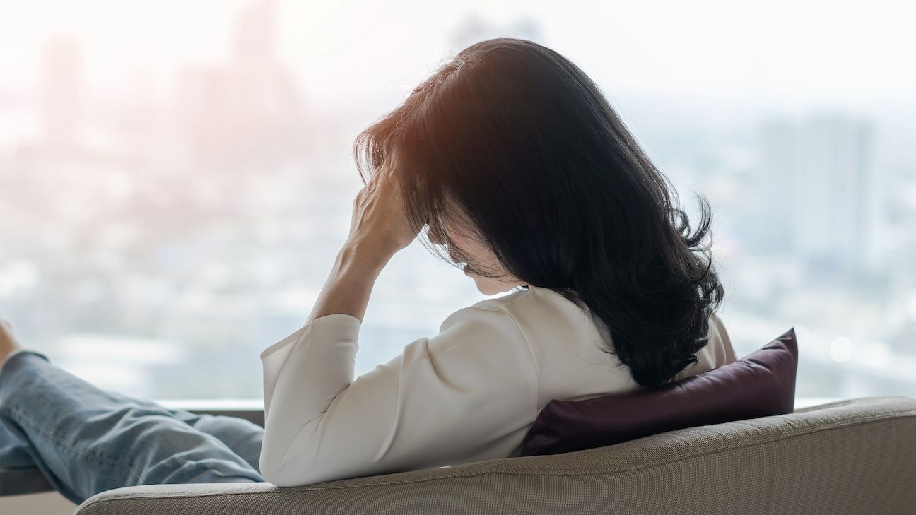 Anxiety disorder menopause woman, stressful depressed, panic attack person with mental health illness, headache and migraine pain sitting on armchair in domestic home