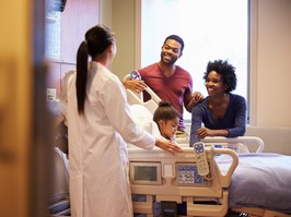 Pediatrician Visiting Parents And Child In Hospital Bed