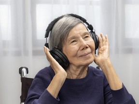 Asian senior woman listening music with headphone at home